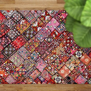 Puede incluir: Una alfombra de patchwork colorida con un patrón geométrico en tonos de rojo, rosa, azul y verde. La alfombra está hecha de retazos de tela cosidos juntos en un patrón de diamante.