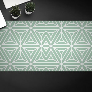 Op de afbeelding: Een groene en witte geometrische gepatroneerde bureau mat. Het patroon is gemaakt van herhalende driehoeken en sterren.