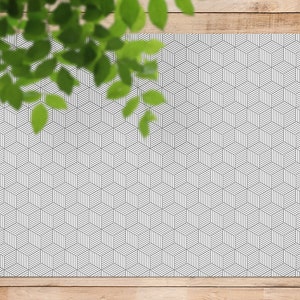 Può includere: Un tappeto geometrico bianco e grigio con un motivo a cubo ripetuto.