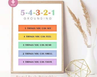 May include: A framed print with the text "5-4-3-2-1 GROUNDING" in colorful lettering. Below, the print lists prompts: "5 THINGS YOU CAN SEE," "4 THINGS YOU CAN FEEL," "3 THINGS YOU CAN HEAR," "2 THINGS YOU CAN SMELL," and "1 THINGS YOU CAN TASTE." The print is by "Pastel Peelz Printables."