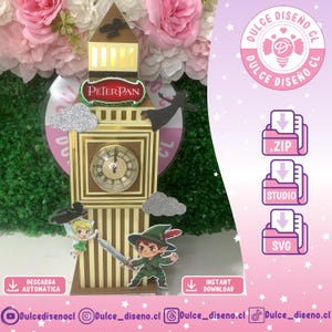 Puede incluir: Un modelo decorativo de papel de la torre del reloj Big Ben con temática de Peter Pan. La estructura incluye una esfera de reloj, nubes de purpurina plateada y recortes de Peter Pan y Campanilla. El texto incluye Peter Pan y Dulce Diseño CL.