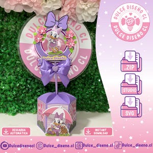 Puede incluir: Decoración de fiesta temática de Daisy Duck en morado y rosa. La decoración incluye un letrero redondo con el texto "Dulce Diseño", un lazo y una caja hexagonal con ilustraciones de Daisy Duck. La imagen también muestra opciones de descarga de archivos.