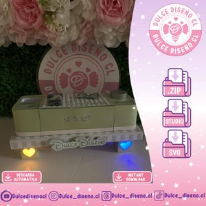 Puede incluir: Una máquina Cricut verde claro con un lazo decorativo y la palabra "Cricut" en plata. La máquina se encuentra sobre una plataforma con luces en forma de corazón y cuadrado. La imagen incluye el texto "Dulce Diseño CL".