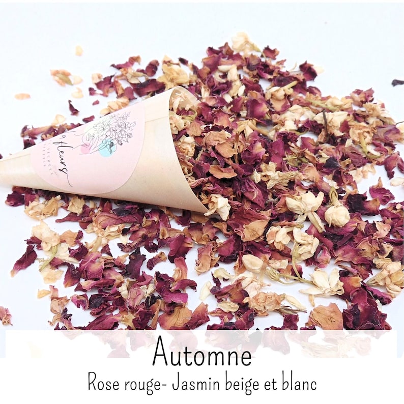 May include: A tan paper cone filled with dried red rose petals and white jasmine flowers. The cone features a pink circular label with a line art illustration and the text "fleurs". The text "Automne Rose rouge- Jasmin beige et blanc" is below.
