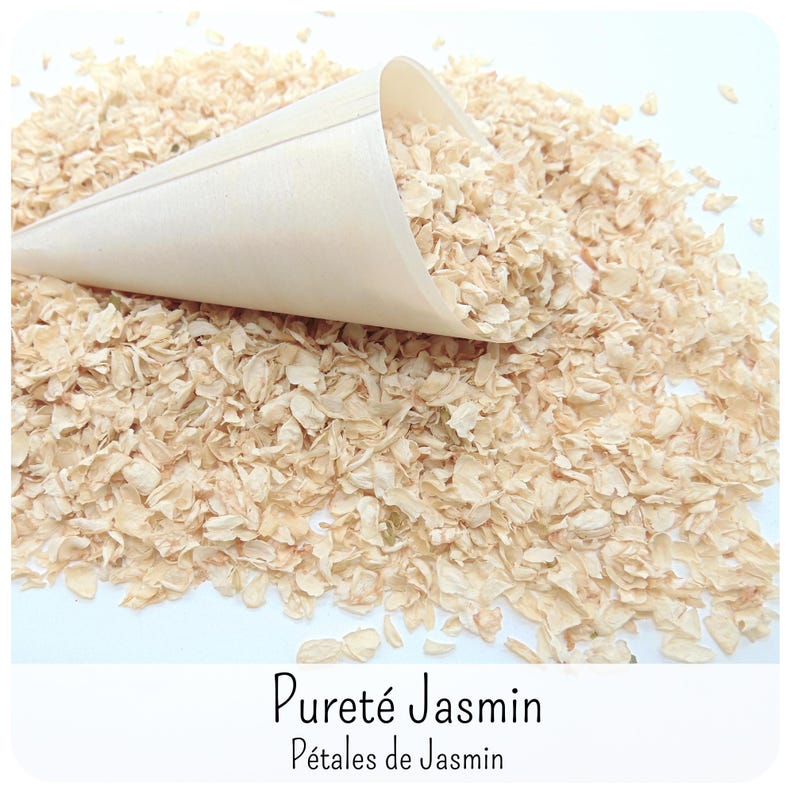 May include: A light beige wooden cone filled with and resting on a pile of dried, off-white jasmine petals. The text Puret&eacute; Jasmin P&eacute;tales de Jasmin is printed in black at the bottom of the image against a white background.