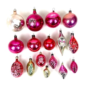 May include: A collection of fifteen vintage glass Christmas ornaments in various shapes and sizes. The set includes round, teardrop, and ribbed baubles in shades of pink, red, silver, and gold, each featuring a metal cap for hanging purposes.