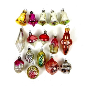 Op de afbeelding: Een verzameling vintage kerstversieringen in diverse vormen en kleuren. Bevat bel-, druppel- en bolontwerpen in goud, roze, rood, zilver en groen. Elke versiering heeft een metalen dop en lus om op te hangen, ideaal voor de feestdagen.
