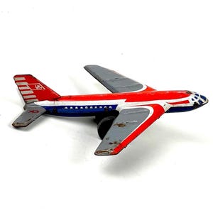 May include: Vintage toy airplane with a red, white, and blue color scheme. The metal plane features gray wings and tail, with a black wheel. The tail has a logo. A classic collectible.