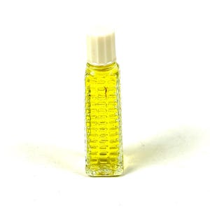 Op de afbeelding: Een kleine, rechthoekige glazen fles met een textuurpatroon en een witte dop. De fles is gevuld met een gele vloeistof. Het ontwerp van de fles doet denken aan een maïskolf.