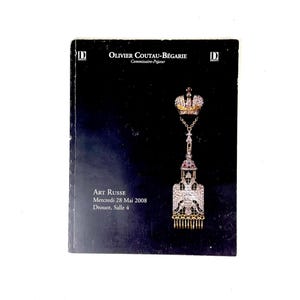 May include: A dark blue catalog cover featuring the text "OLIVIER COUTAU-BÉGARIE" and "ART RUSSE". The cover displays a jeweled pendant with a crown, a detailed eagle design, and a series of dangling gold elements. The date "Mercredi 28 Mai 2008" is also visible.