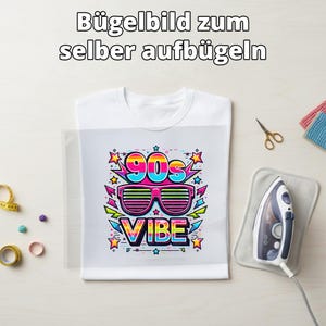 Könnte beinhalten: Weißes T-Shirt mit einem farbenfrohen 90er-Jahre-Motiv. Das Design zeigt eine Sonnenbrille, das Wort "VIBE" und den Text "90s" in einem lebendigen, Retro-Stil. Ein Bügeleisen, eine Schere und andere Bastelutensilien sind sichtbar.