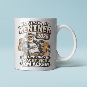 Könnte beinhalten: Ein weißer Keramikbecher mit einer Grafik einer lächelnden Person mit Hut, Sonnenbrille und Blumenhemd, die auf einem Stuhl sitzt. Der Text lautet: ES IST SOWEIT RENTNER 2026, ENDLICH FREIHEIT und DER ALTE KNACKER MACHT SICH VOM ACKER!