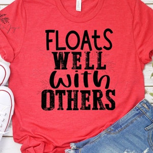 Puede incluir: Camiseta roja con un gráfico negro que dice "Floats Well With Others".