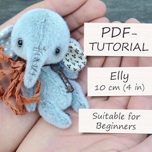 Könnte beinhalten: Ein graues und weißes Plüschelefantenspielzeug mit einem braunen Band um den Hals. Das Spielzeug ist 10 cm (4 Zoll) groß und für Anfänger geeignet. PDF - TUTORIAL Elly 10 cm (4 in) Für Anfänger geeignet