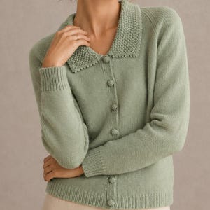 May include: A sage green long-sleeve cardigan featuring a textured knit collar, a button-down front with matching sage green buttons, and ribbed cuffs and hem. The garment is crafted from a soft knit material with a consistent solid color.