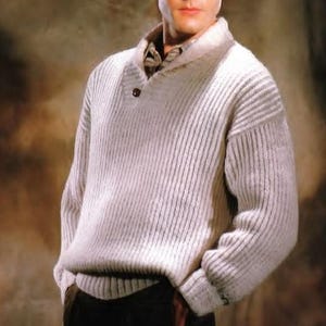 May include: A light gray, ribbed knit sweater with a shawl collar and a single brown button closure. The sweater has a textured appearance and long sleeves. The collar reveals a glimpse of a patterned shirt underneath. The overall style is classic and warm.