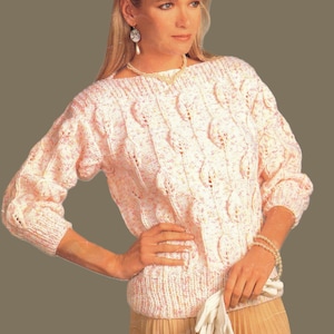 Könnte beinhalten: Ein hellrosa Strickpullover mit Bootsausschnitt und Dreiviertelärmeln. Der Pullover hat ein strukturiertes Blättermuster auf der Vorderseite und den Ärmeln. Das Kleidungsstück ist aus einem weichen, gesprenkelten Garn gefertigt, wodurch eine subtile Farbvariation entsteht.