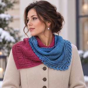 May include: A two-toned triangular crochet shawl featuring a deep magenta section and a blue section with a decorative scalloped edge. The shawl is draped around the neck over a beige coat with brown buttons, showcasing a textured knit pattern.