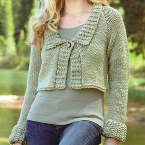 Op de afbeelding: Een lichtgroen gebreid vest met een kraag en knoopsluiting. De mouwen hebben geribde manchetten. Het vest is een cropped model en het breisel heeft een getextureerde uitstraling.