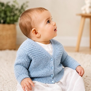 May include: A light blue knitted cardigan featuring a textured waffle stitch pattern, a V-neckline, long sleeves with ribbed cuffs, and a front button closure with four matching light blue buttons, worn over a plain white shirt.
