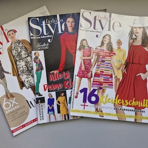 Könnte beinhalten: Drei Modemagazine mit dem Titel "fashion Style" auf dem Cover. Die Magazine zeigen Models in verschiedenen Kleidungsstilen. Der Text auf dem Cover lautet "Mode zum Selbernähen" und "Alle Deine Kleider". Die Magazine sind übereinander gestapelt.