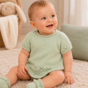 Può includere: Una tutina in maglia per neonati color verde salvia chiaro con maniche corte e scollo rotondo. Il capo presenta un delicato motivo traforato a chevron lungo l'orlo e i bordi delle maniche, completato da scarpine in maglia abbinate.