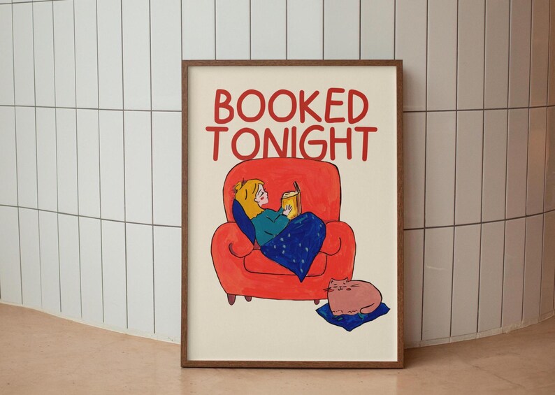 Puede incluir: Una impresi&oacute;n art&iacute;stica enmarcada con las palabras "BOOKED TONIGHT" en rojo. La ilustraci&oacute;n representa a una persona leyendo en un sill&oacute;n rojo, con un gato descansando sobre un coj&iacute;n azul. La obra tiene un estilo caprichoso y caricaturesco.