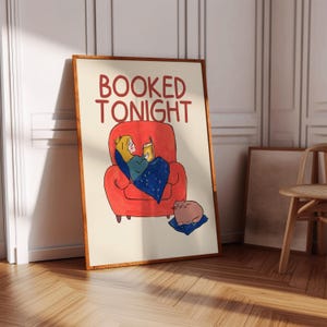 Puede incluir: Una impresi&oacute;n art&iacute;stica enmarcada con el texto "BOOKED TONIGHT" en rojo. La ilustraci&oacute;n representa a una persona relaj&aacute;ndose en un sill&oacute;n rojo, sosteniendo una bebida y cubierta con una manta azul. Un gato descansa sobre un coj&iacute;n azul cerca.