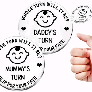 K&ouml;nnte beinhalten: Zwei silberne m&uuml;nzf&ouml;rmige Token mit schwarzem Text und Bildern. Eine Seite lautet "Whose turn will it be?" mit einem Babygesicht und "Daddy's turn" und "Flip for your fate". Die andere Seite lautet "Whose turn will it be?" mit einem Babygesicht und "Mummy's turn" und "Flip for your fate".
