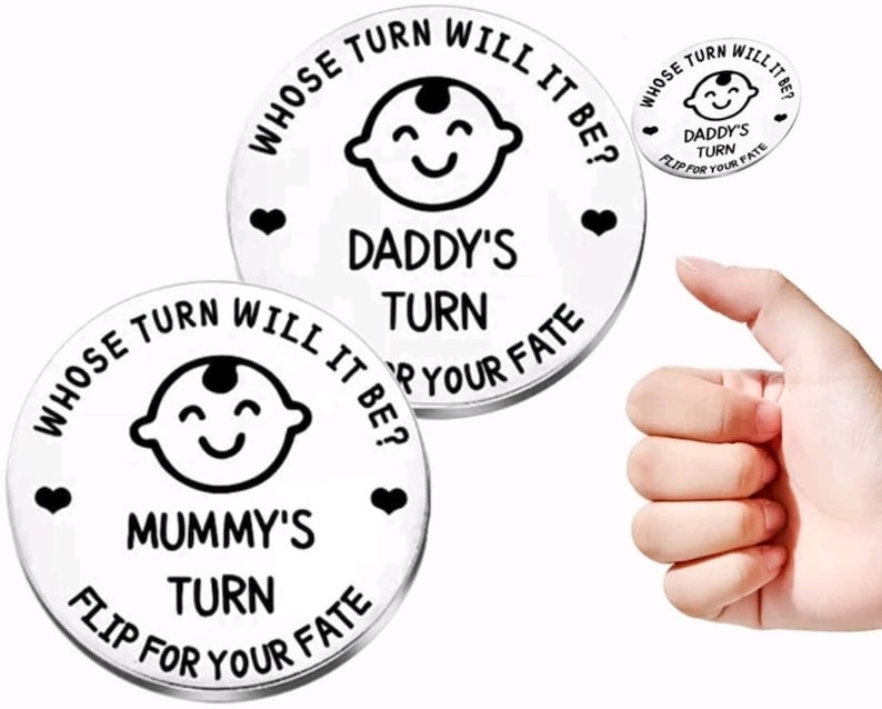 K&ouml;nnte beinhalten: Zwei silberne m&uuml;nzf&ouml;rmige Token mit schwarzem Text und Bildern. Eine Seite lautet "Whose turn will it be?" mit einem Babygesicht und "Daddy's turn" und "Flip for your fate". Die andere Seite lautet "Whose turn will it be?" mit einem Babygesicht und "Mummy's turn" und "Flip for your fate".