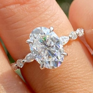 May include: A silver engagement ring with a large oval-shaped diamond and smaller pear-shaped diamonds on the band.