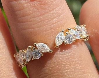 May include: A gold ring with a delicate design featuring marquise-shaped clear stones set in a curved band.