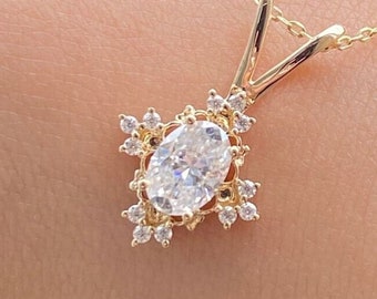 May include: A gold chain necklace with a pendant featuring a large oval-shaped clear stone surrounded by smaller clear stones in a floral design.