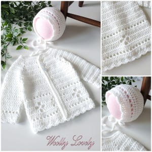 Op de afbeelding: Een witte, gehaakte baby-vest en muts set. Het vest heeft lange mouwen en een geschulpte zoom, met decoratief ajourwerk. De muts is rond met een strik. De tekst "Woolly Lovely" staat rechtsonder.