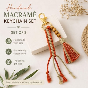 May include: A macramé keychain set of two featuring orange and beige cotton cord, gold-tone metal lobster clasps, and wooden beads. The text reads: Handmade MACRAMÉ KEYCHAIN SET, SET OF 2, Handmade with care, Eco-friendly cotton cord, Thoughtful gift idea, Boho, Minimal, Everyday Essential.