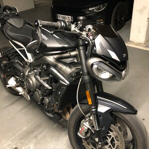 Może przedstawiać: Czarny i srebrny motocykl z czarnym siedzeniem i czarną szybą. Motocykl ma srebrną ramę i czarne koła. Motocykl jest zaparkowany w garażu.