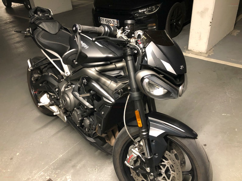 Może przedstawiać: Czarny i srebrny motocykl z czarnym siedzeniem i czarną szybą. Motocykl ma srebrną ramę i czarne koła. Motocykl jest zaparkowany w garażu.