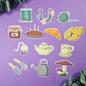 Op de afbeelding: Een set van 12 geïllustreerde stickers met verschillende ontwerpen, waaronder een pot jam, een theepot, een croissant, een bijenkorf, een gieter, een paddenstoel, een theezakje, een spoel garen, een hoefijzer, een kop en schotel en tuingereedschap. De stickers zijn op een paarse achtergrond.