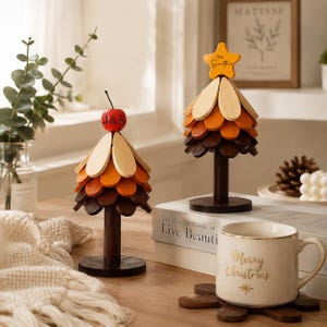 May include: Two decorative wooden trees with layered, petal-shaped branches in shades of cream, orange, and dark brown. The left tree is topped with a red apple marked J&S, while the right tree features a yellow star labeled The Smiths.