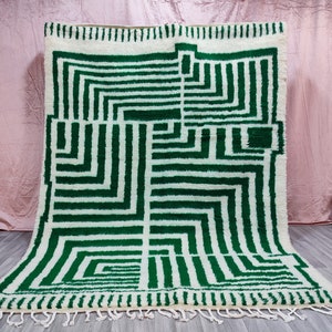 May include: A white and green geometric patterned rug with fringe. The rug has a modern design with a white background and green lines.