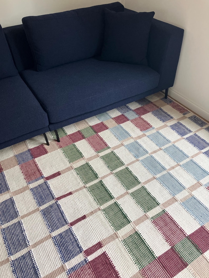 May include: A blue sectional sofa with a checkered rug in shades of blue, green, red, and white.
