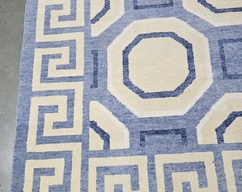 May include: A blue and white patterned rug with a geometric design. The rug has a fringe border.