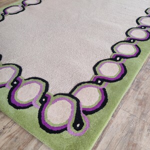 Hand tufted wool rug with green border and purple chain pattern on neutral background, modern designer area rug for living room or bedroom