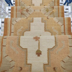 May include: A beige and brown patterned rug with a geometric design. The rug is laid out on a set of stairs.