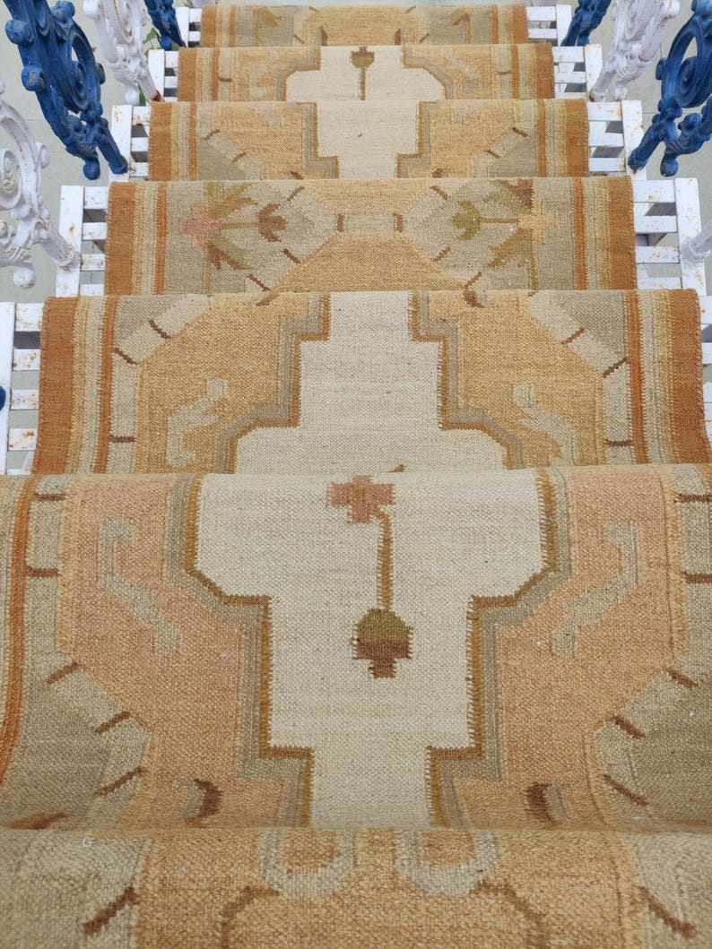 May include: A beige and brown patterned rug with a geometric design. The rug is laid out on a set of stairs.