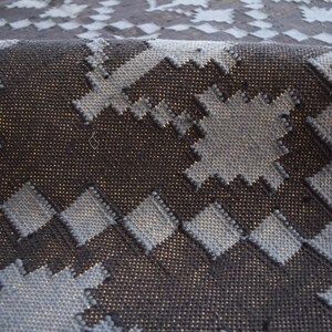 Puede incluir: Primer plano de una alfombra tejida con un patr&oacute;n geom&eacute;trico en tonos azules y negros. La alfombra tiene una superficie texturizada y un aspecto ligeramente desgastado.