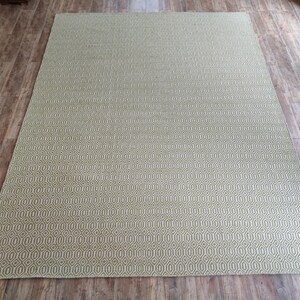 May include: A green and white patterned rug with a geometric design. The rug is made of a woven material and has a soft texture.