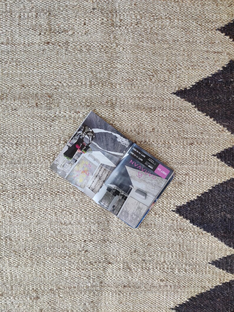 K&ouml;nnte beinhalten: Ein beige-schwarzer Teppich mit einem Magazin darauf. Das Magazin ist auf einer Seite mit dem Text "NV Magazine" und "Style Libre" ge&ouml;ffnet.