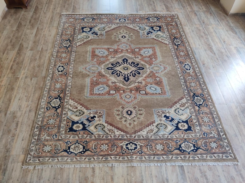 May include: A traditional Persian rug with a beige background and intricate floral patterns in shades of blue, red, and brown. The rug has a fringed border and a central medallion.