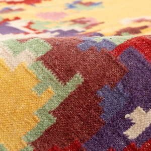 K&ouml;nnte beinhalten: Nahaufnahme eines bunten gewebten Teppichs mit geometrischem Muster. Der Teppich ist aus Wolle und hat eine Vielzahl von Farben, darunter Rot, Gelb, Gr&uuml;n, Blau und Wei&szlig;.